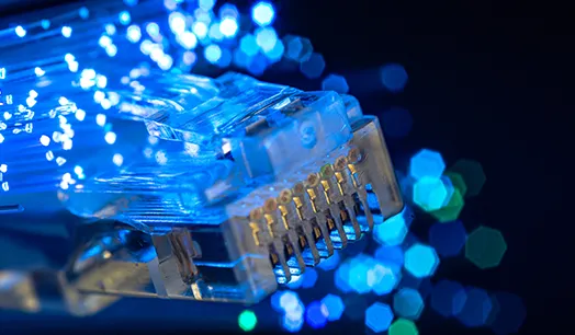 Złącza sieciowe RJ45 na tle podświetlonych włókien światłowodowych